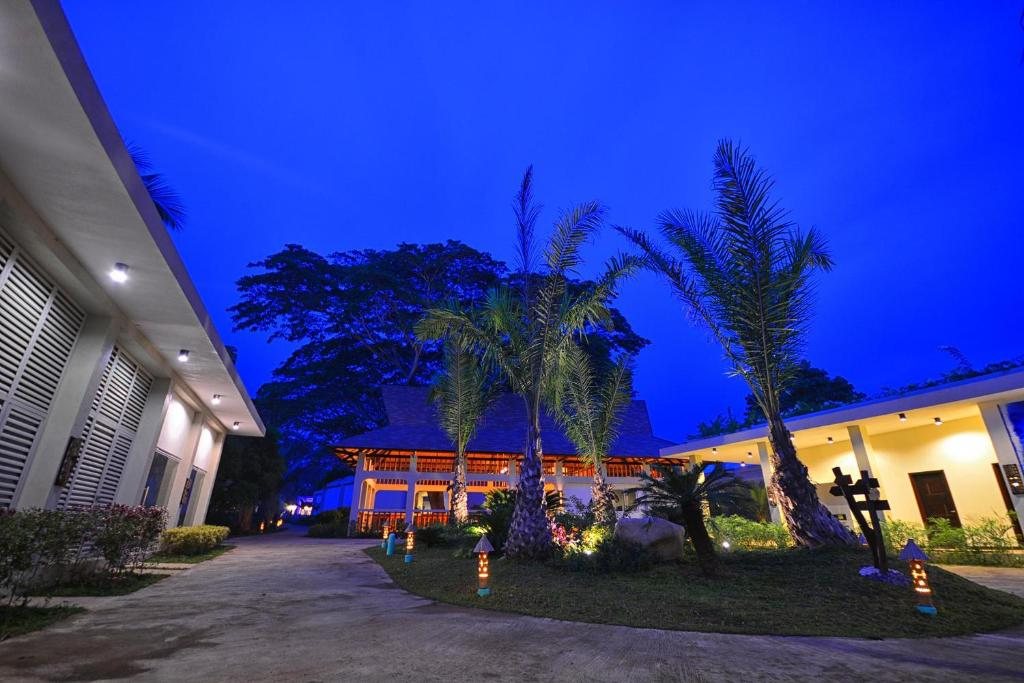 Lit garden pathway at Munting Paraiso lined with palm trees at dusk