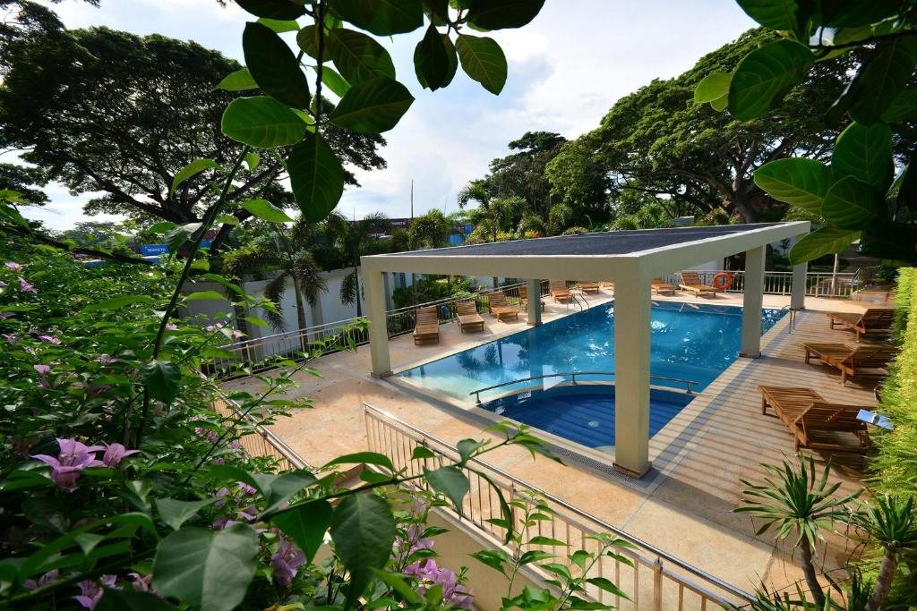 Elevated view of Munting Paraiso's pool and pergola framed by tropical foliage and bougainvillea