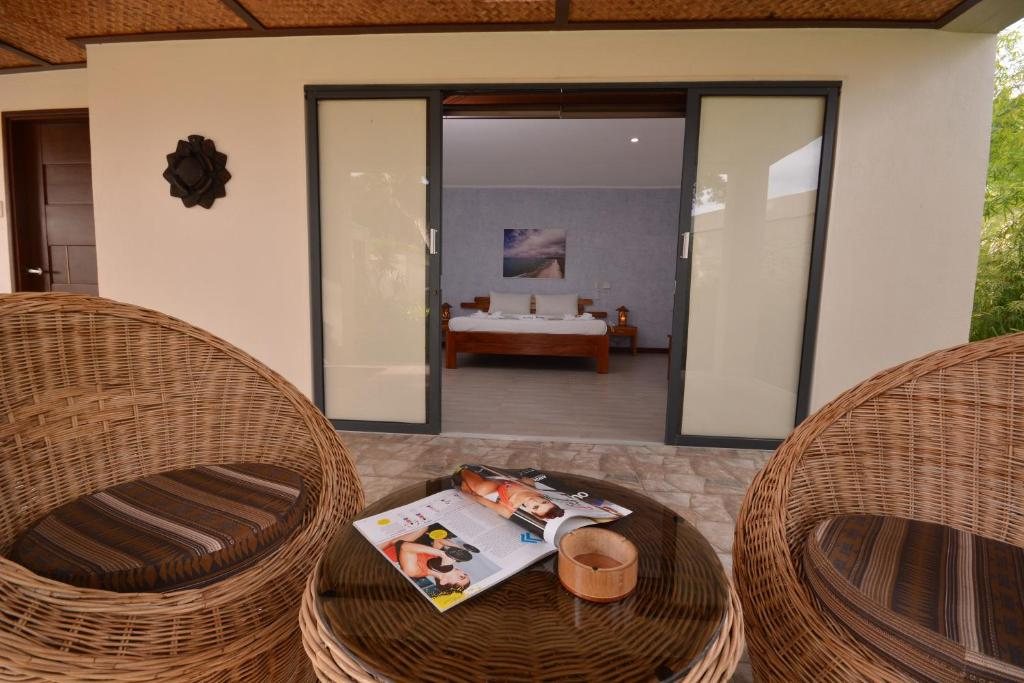 Private veranda with wicker furniture opening into a Superior Bungalow bedroom at Munting Paraiso