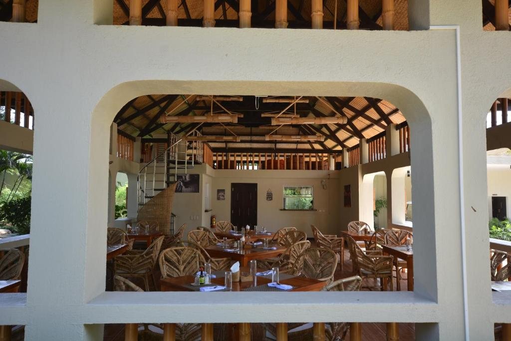 Open-air restaurant and dining area at Munting Paraiso with bamboo roofing and wooden tables