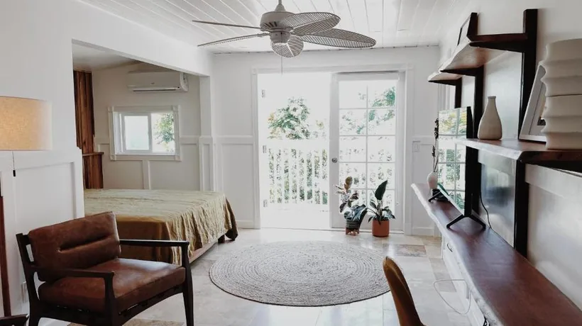 Guest room at Honomu Inn with sitting area, ceiling fan and French doors to the balcony