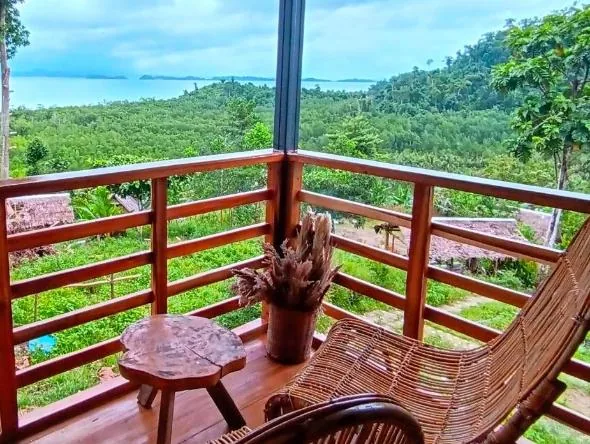 Corner balcony at The View - Jungle Lodges, Port Barton, with two rattan chairs and a small table looking out over jungle canopy to the sea near San Vicente, Palawan
