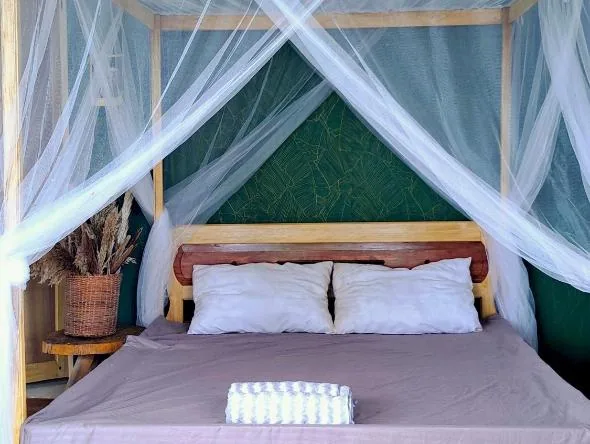 Second guest room at The View - Jungle Lodges, Port Barton, showing a mosquito-net canopy bed with tan linens against a dark green patterned wall