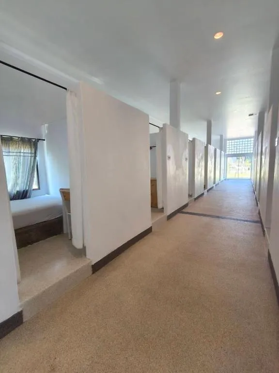 Air-conditioned mixed dormitory corridor at Canary Guesthouse with partitioned bed bays and a terrazzo floor