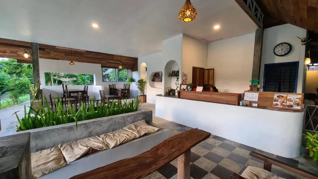 Open-air reception and lounge at Canary Guesthouse with a white counter, cushioned concrete bench and checkerboard floor