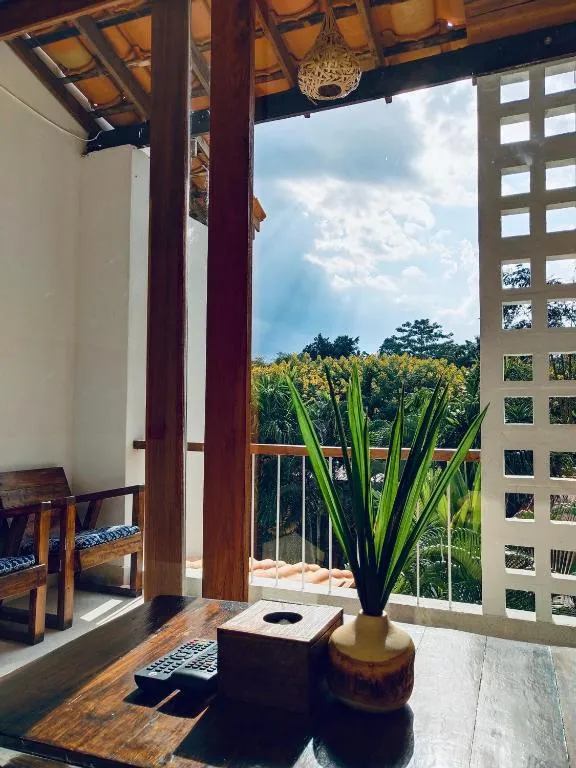 Upper-floor balcony at Canary Guesthouse with wooden furniture, a breeze-block wall and a view over trees to the hills