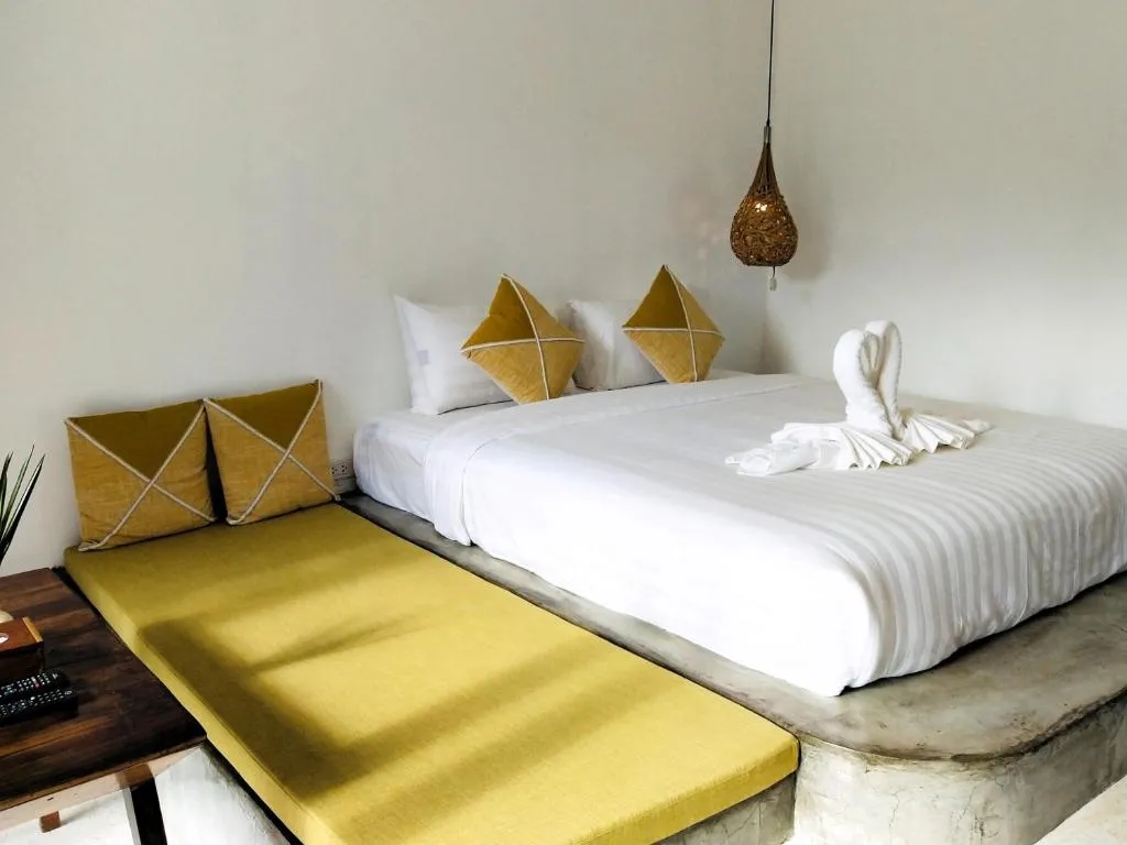 Room at Canary Guesthouse with a white double bed, towel swan, mustard daybed cushions and a woven pendant lamp