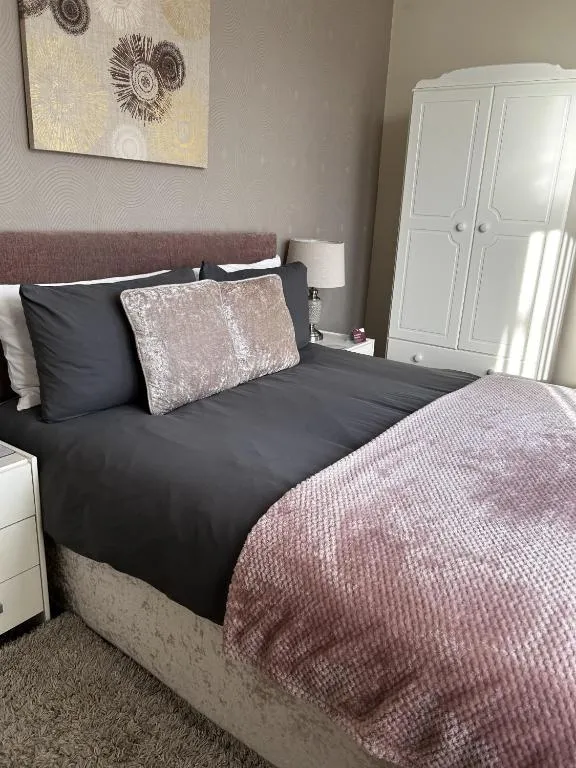 Double room at The Inglewood Hotel with a grey upholstered headboard, blush velvet throw and cushions, and a white wardrobe