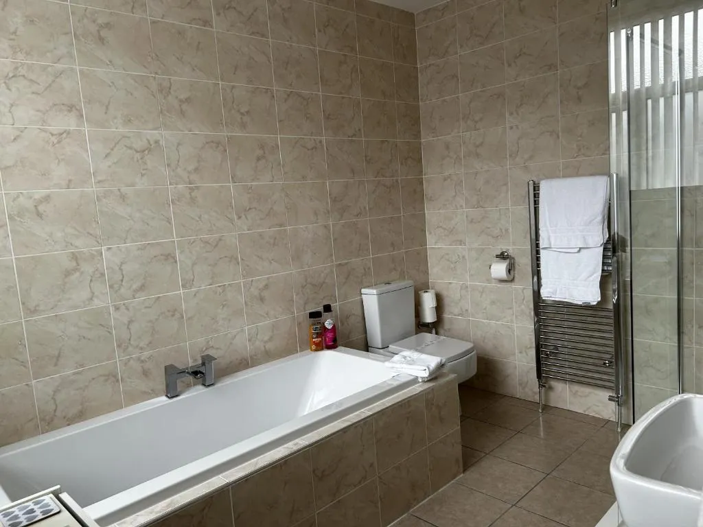 Deluxe King en suite at The Inglewood Hotel with a full-size bathtub, a separate glass shower and a chrome heated towel rail