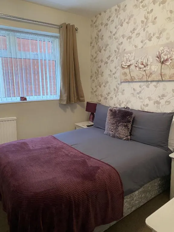 Standard double at The Inglewood Hotel with a plum velvet throw, grey bedding, floral wallpaper and blossom wall art