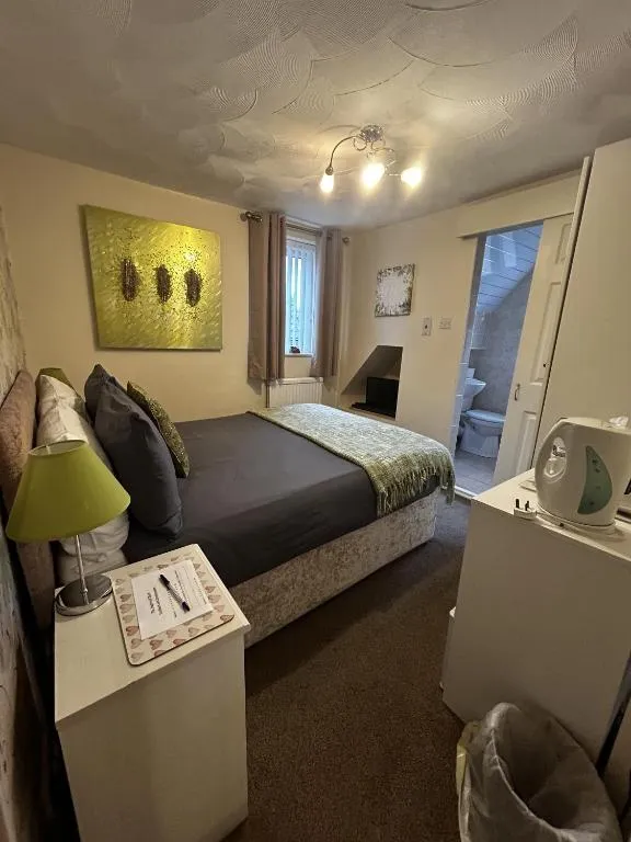 Room at The Inglewood Hotel with a lime-green lamp, green abstract canvas, grey bedding and a white bedside unit