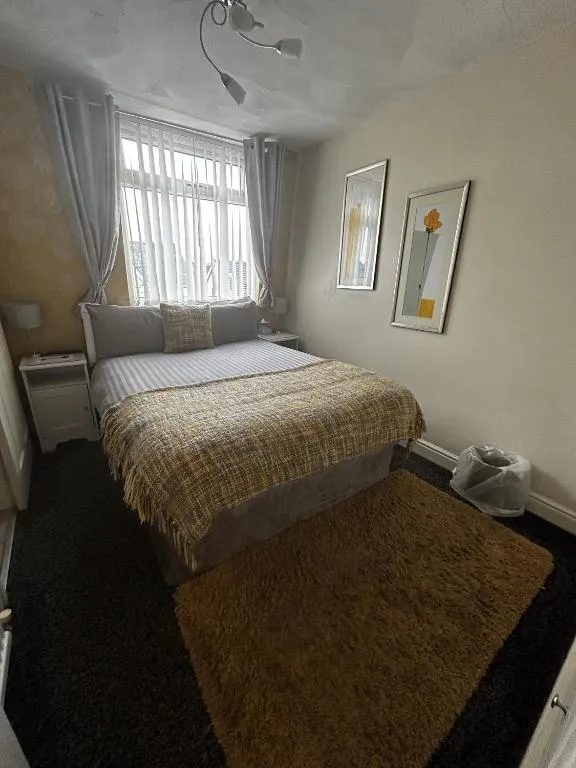 Compact double room at The Inglewood Hotel with a window, cream walls, framed prints and a patterned mustard bedspread